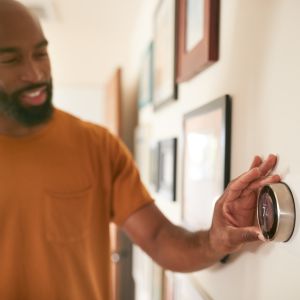 A man controls his home temperature using a smart controller.